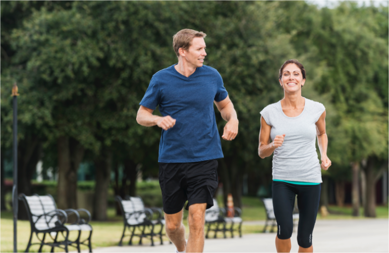 Двойка в добро настроение, която тича и се смее в парка след приложение на Лиотон 1000®
